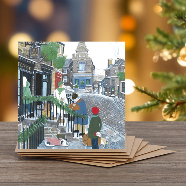 A greeting card by Mani Parkes with people on a street, surrounded by Christmas decorations.