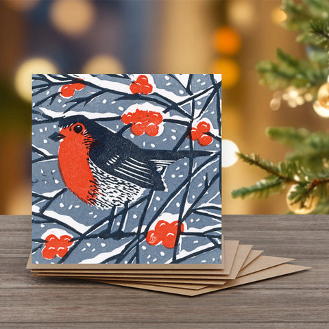 A square winter greeting card featuring a red-breasted robin, blue-gray background, and red berries.