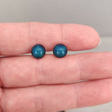 Claire Fernig Spinnaker Glass Mini Teal 925 Silver stud earrings held between fingers