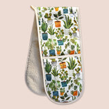 A double-sided oven mitt with a white background and a colorful pattern of potted houseplants on the exterior.